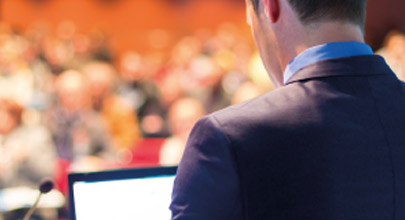 A man in a suit presenting to an audience at an event